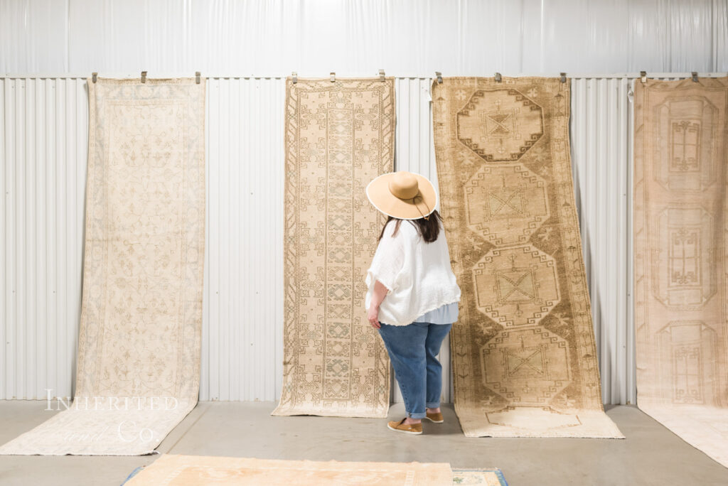 Lauren faces wall of antique Persian rugs at antique market