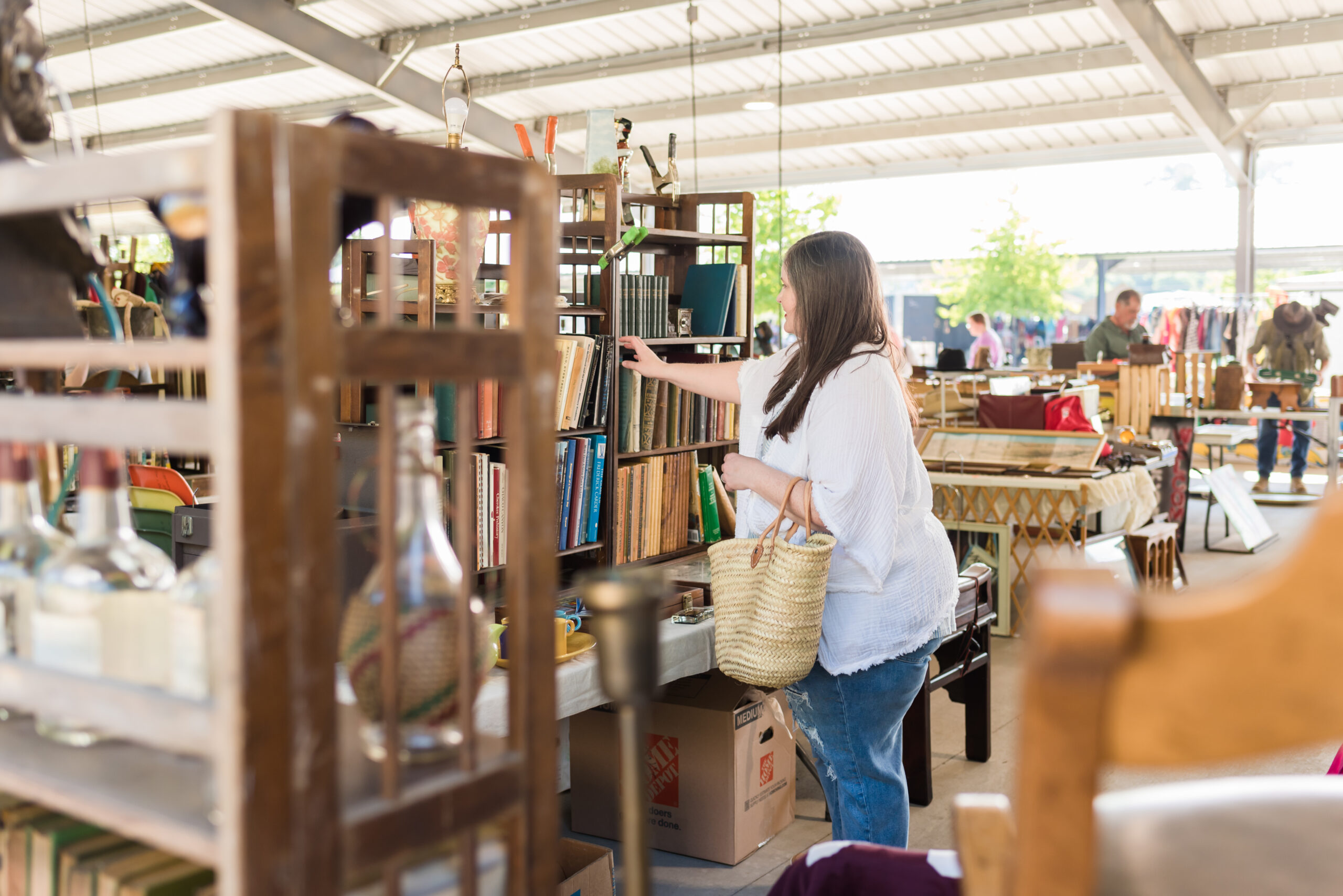 Lauren examines antique books on a shelving unit at an antique market