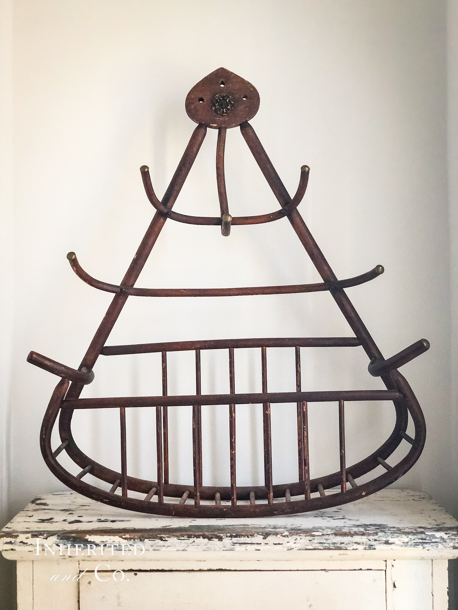 Bentwood hat rack that is triangular in shape and has brass details