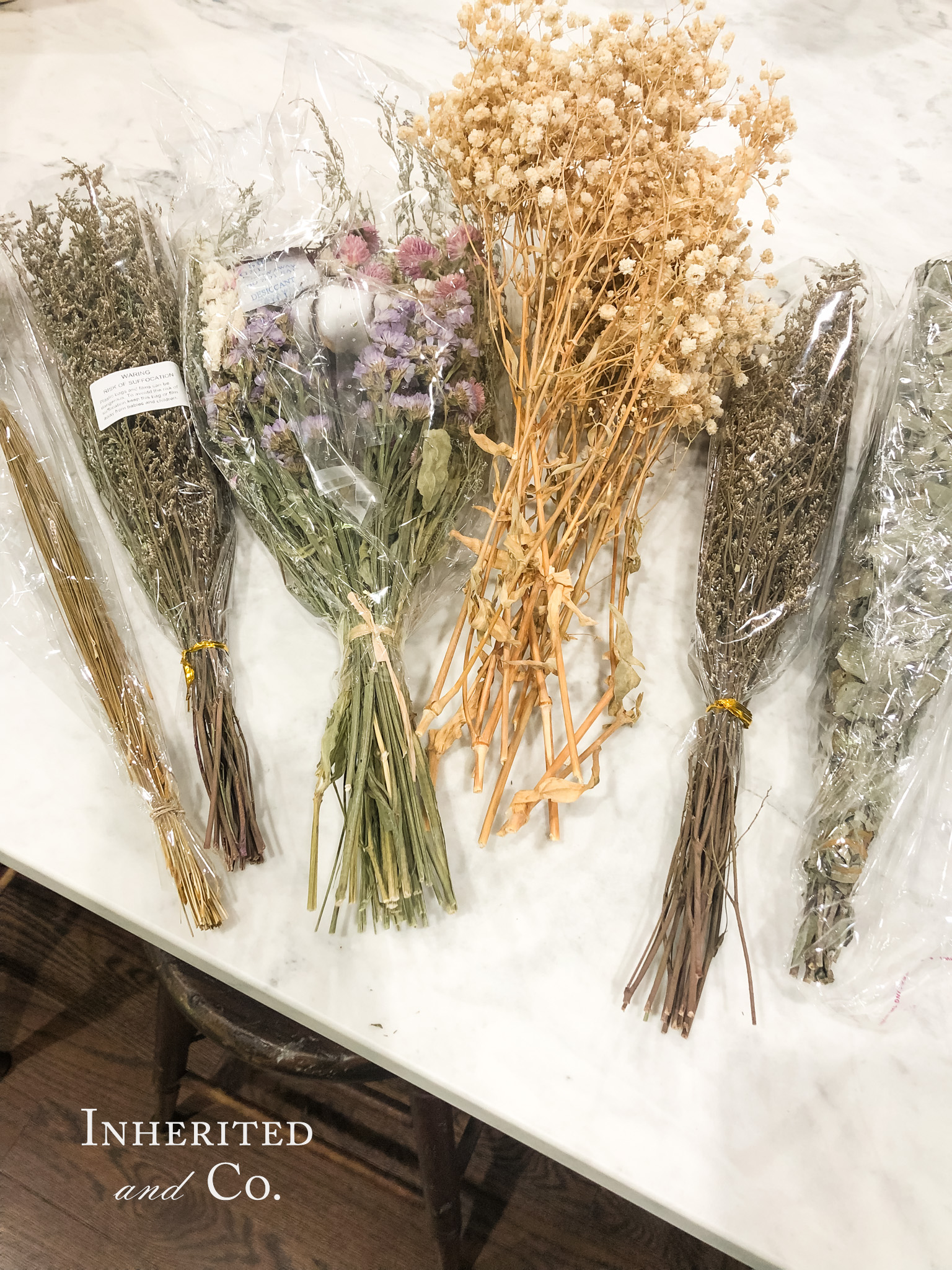 six bundles of dried flowers on a white marble countertop