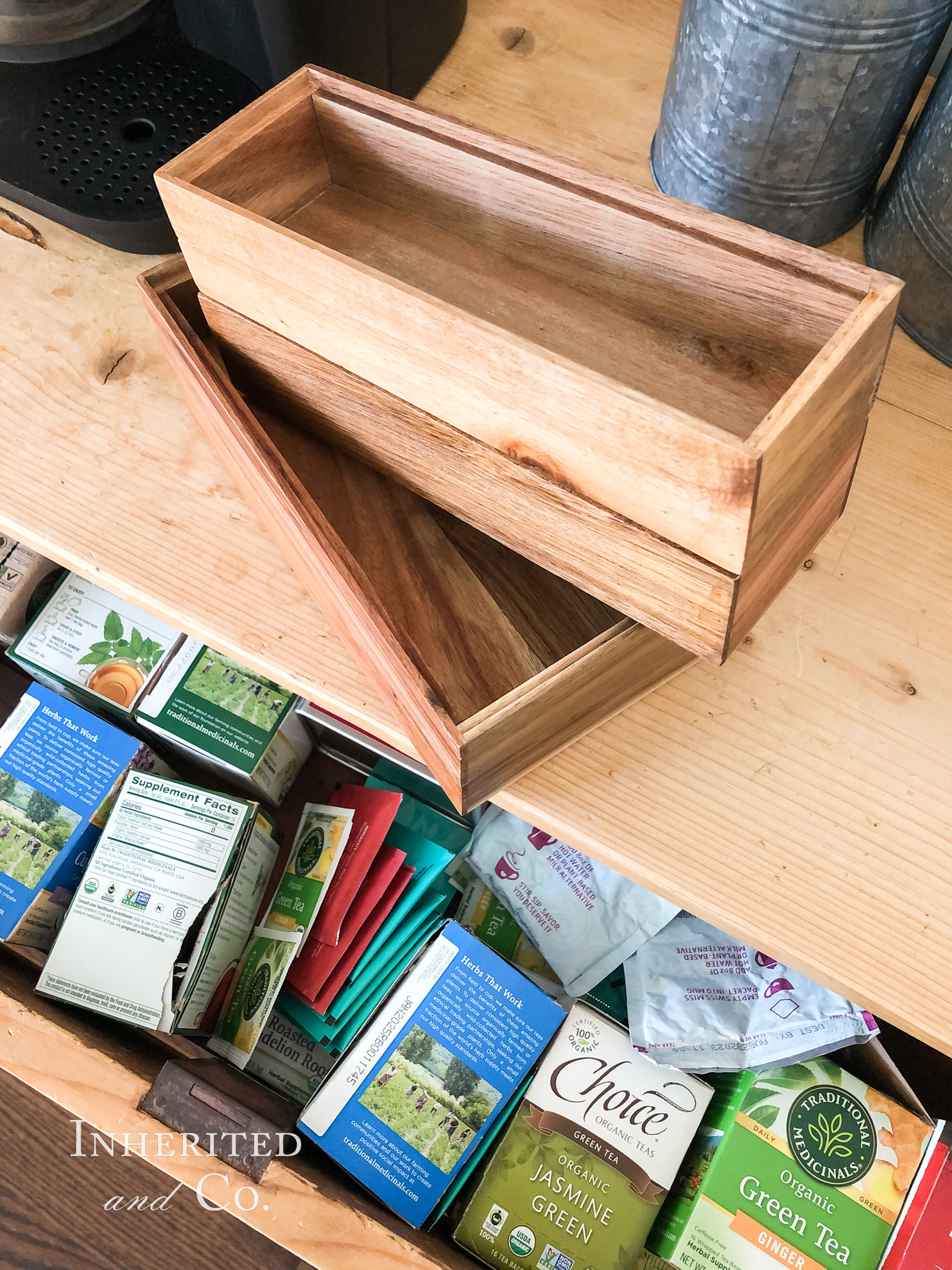 A messy drawer filled with tea bags and acacia organizers above it