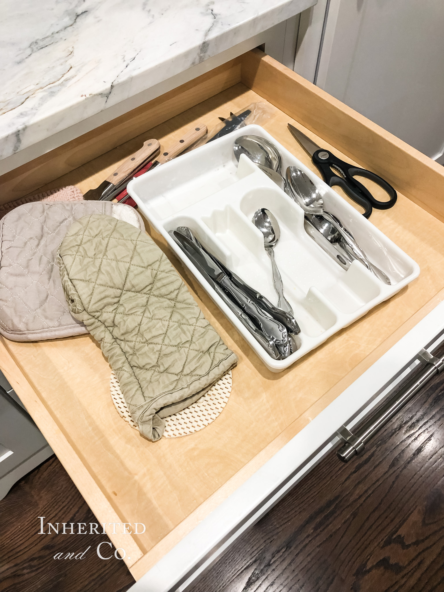 Disorganized kitchen drawer with oven mitt and plastic utensil tray