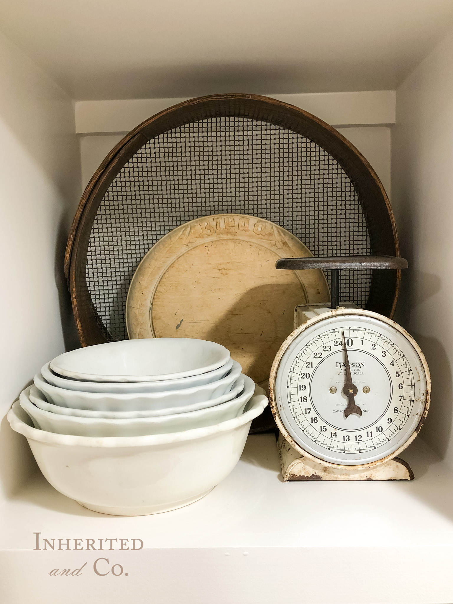 vignette of ironstone bowls, kitchen scale, bread board, and sieve