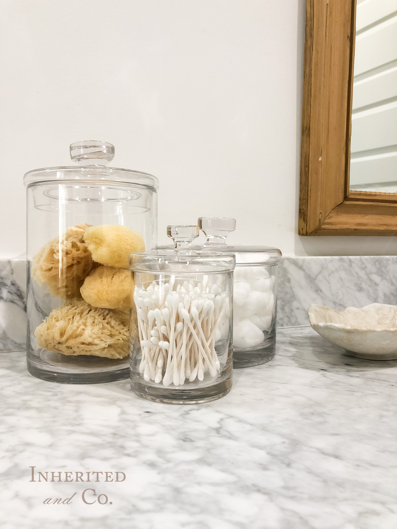 Glass Canisters with sponges, q-tips, and cotton balls on a bathroom countertop