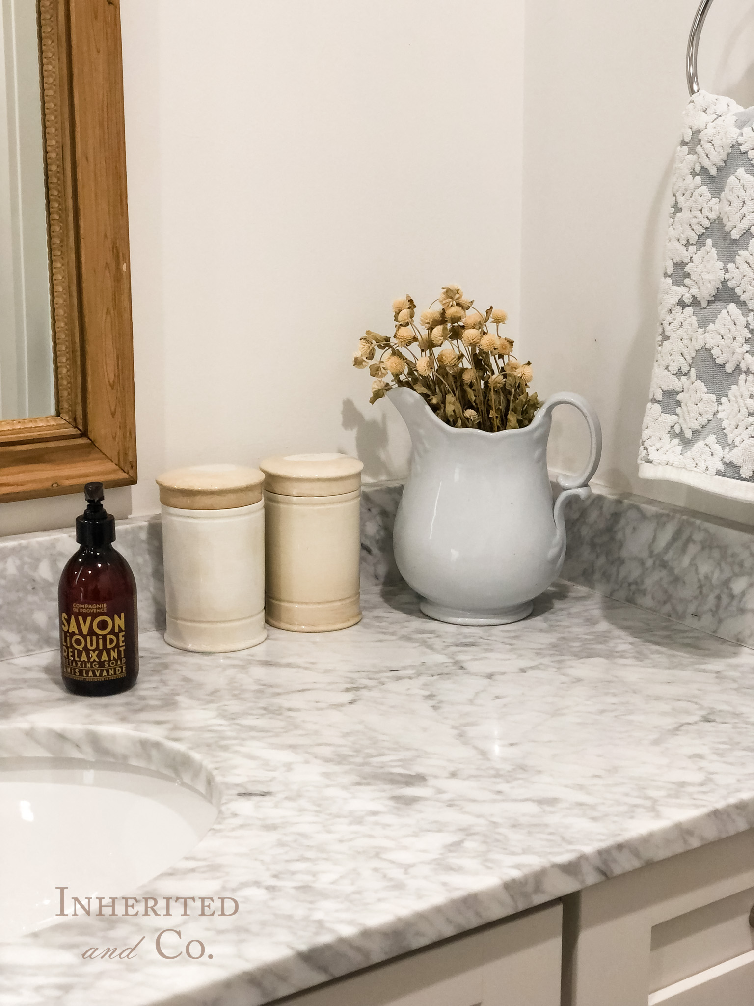 French Pharmacy Jars and an ironstone pitchers used for organization and decor on a bathroom countertop
