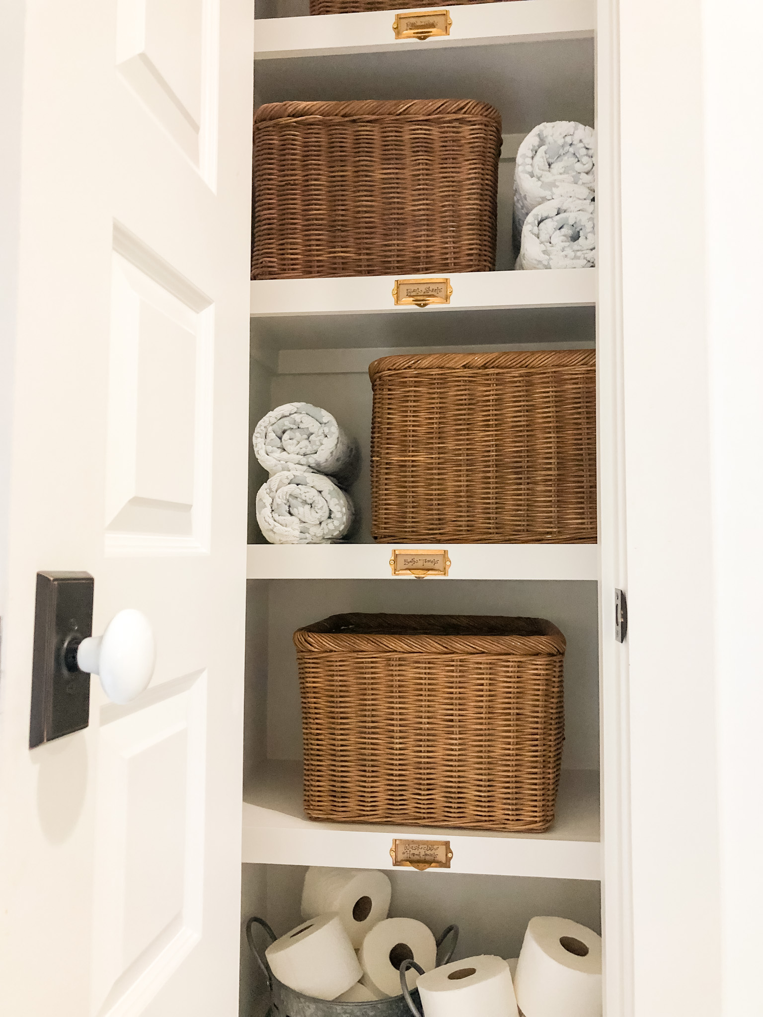 Rattan Baskets and Card Catalog Labels used to organize a Towel Closet