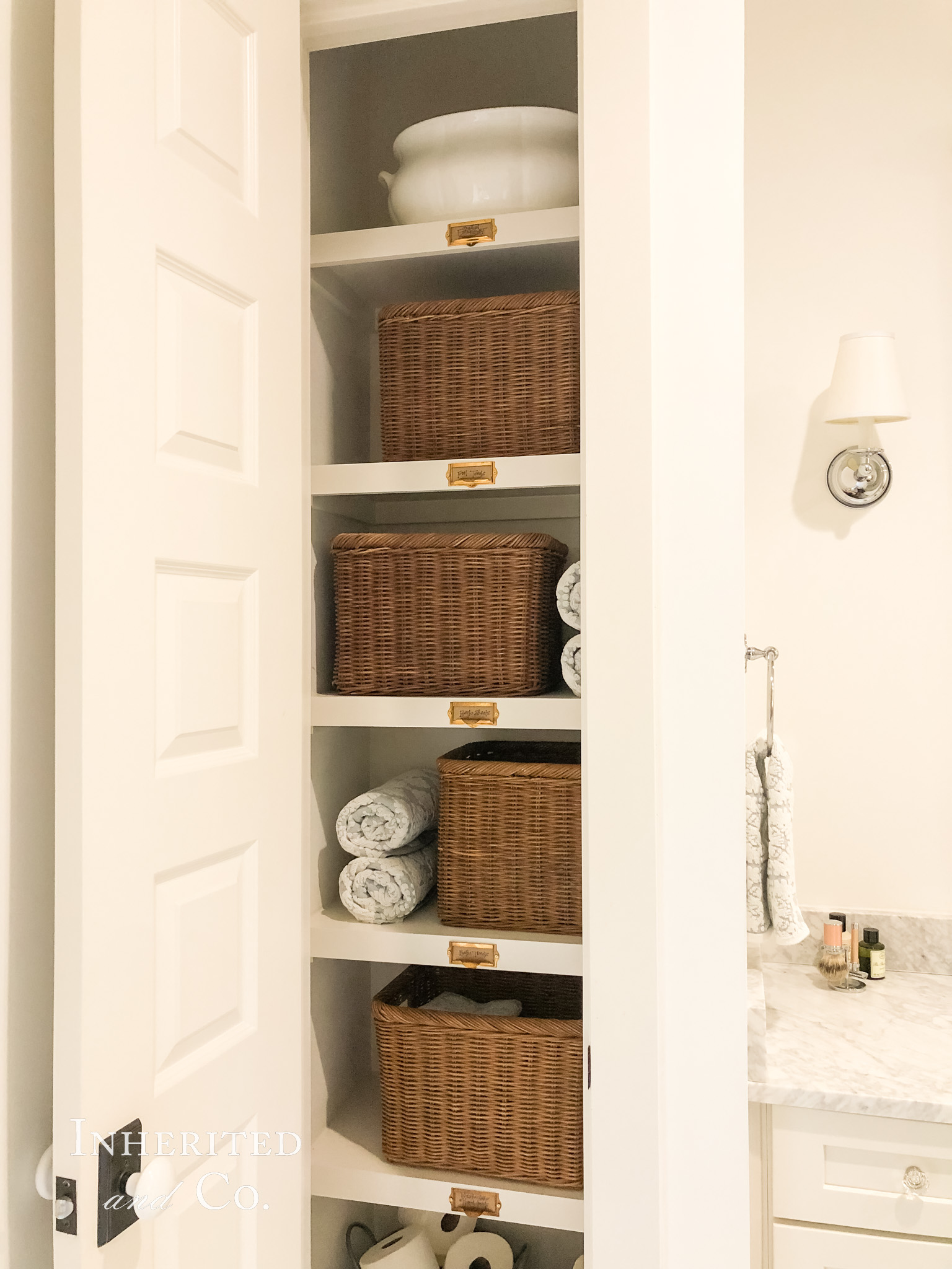 Top shelves in a towel closet, featuring an ironstone footbath and baskets