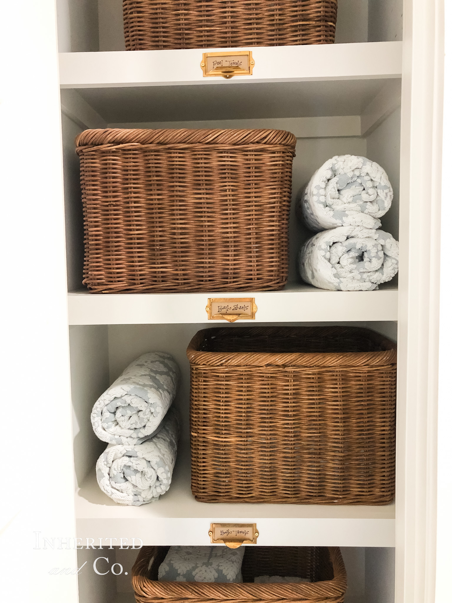 Towel Closet Organization with Rattan Baskets and Antique Card Catalog Labels