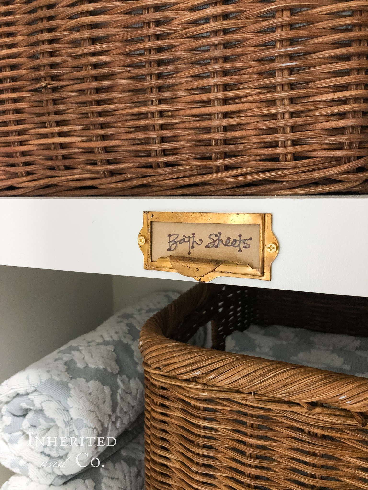 "Bath Sheets" written on a repurposed card catalog label in a linen closet