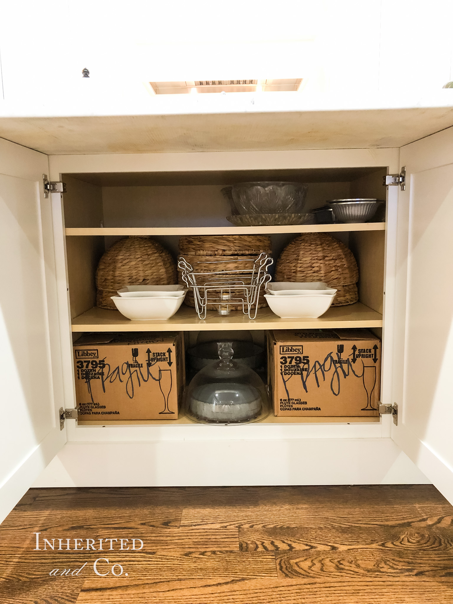 Serving pieces, including items for the Liz Marie QVC line, stored under the kitchen island